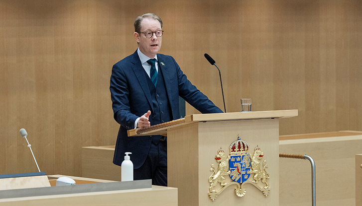 Billström står i talarstolen i riksdagen